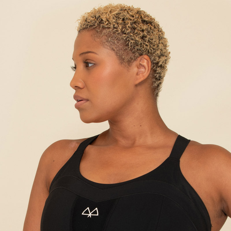 Woman wearing a black sports bra with a logo on a beige background