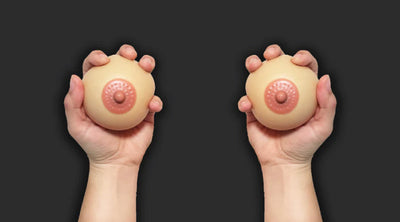 Pair of hands holding two stress balls against a black background