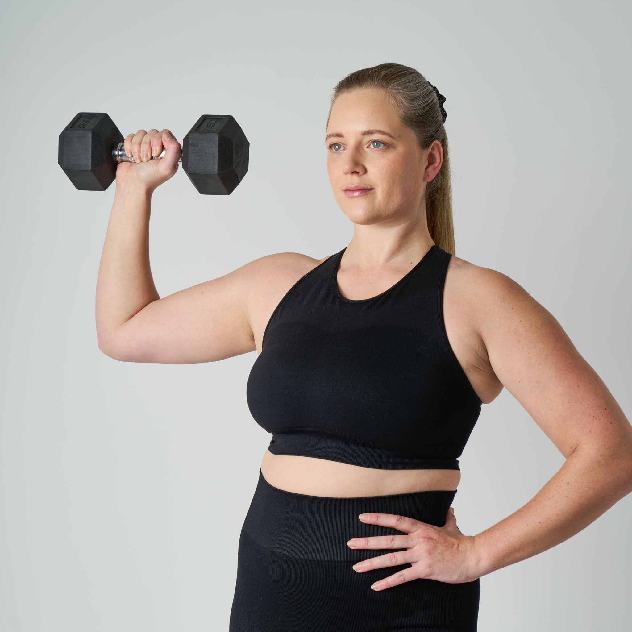 Woman lifting a dumbbell against a plain background