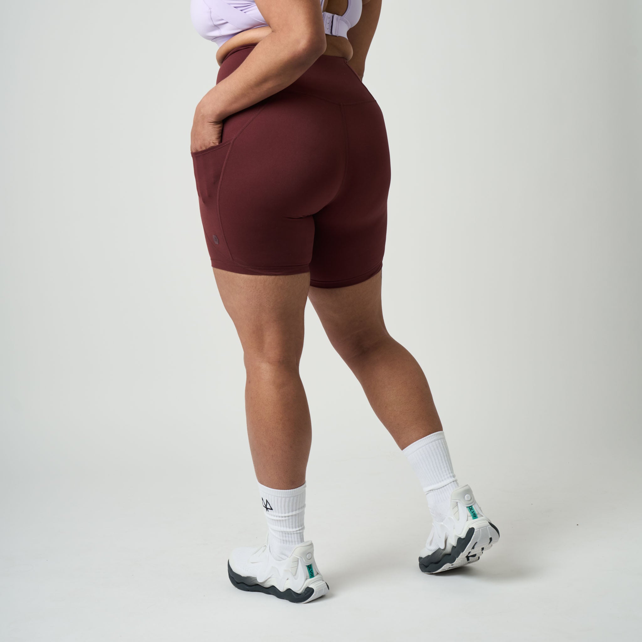 Person wearing maroon athletic shorts on a plain background