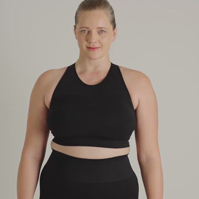 Person wearing a black sports bra with a logo on the back against a gray background